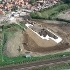 View from above of the north side of the building site. Heavy Machinery are moving mounds of earth.